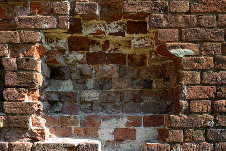 Texture of an old destroyed brick wall from a red brick of an ancient building close up.