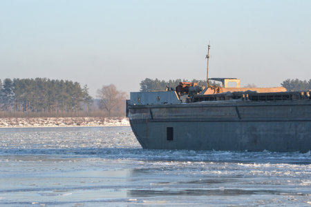 Barge frozen in ice and snow at wintering near the shore, stern close-up. Barge Scene with Chunks of Ice Floating in the Foreground.の写真素材