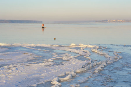 Winter fishing. Ice fisherman fishing in the winter on the river.の写真素材