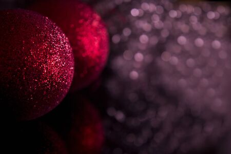 Red Christmas baubles on background of defocused purple lights.の写真素材