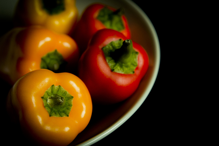 Colorful peppers in white bowl on black background.の写真素材
