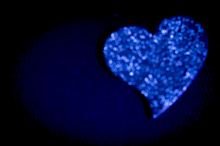 Defocused blue heart on black background.の写真素材