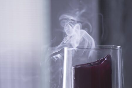 Smoke fading red candle in a glassの写真素材