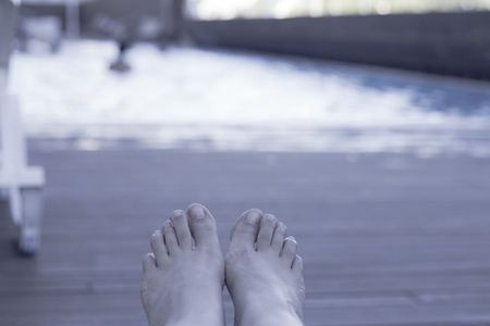 Relaxed atmosphere. Woman feet on chair at the pool.の写真素材