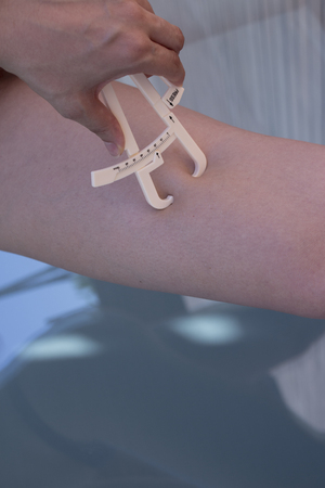 Part of the body of a woman measuring contour and body fatの写真素材