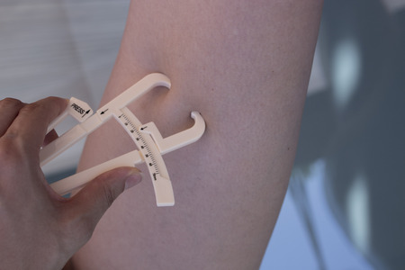 Part of the body of a woman measuring contour and body fatの写真素材