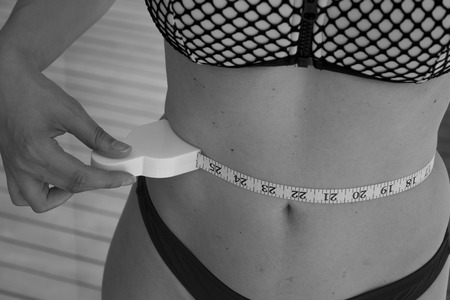 Part of the body of a woman measuring contour and body fat