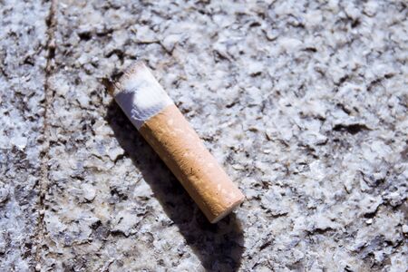 Cigarette butt off on isolated ground. No people.
