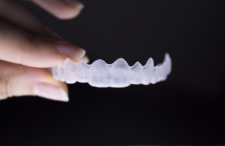 Invisible dental orthodontics held by a womans fingersの写真素材