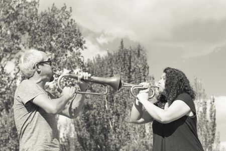 Man and woman playing trumpet on sky backgroundの写真素材