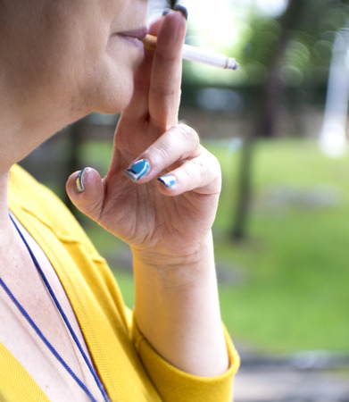 Womans hand holding a cigarette while smokingの写真素材