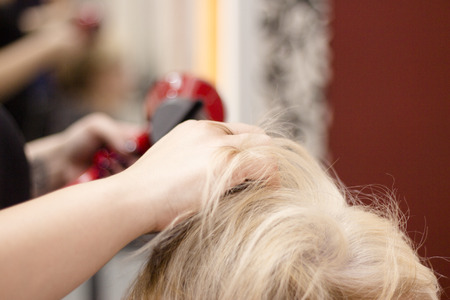 Hairdresser drying hair with red hand dryerの写真素材
