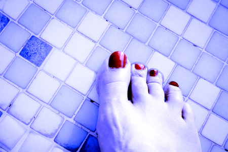 Bare feet of woman with nails painted red. Pool backgroundの写真素材