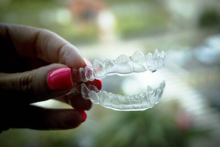 Invisible dental retainer held by womans hand. Copy space
