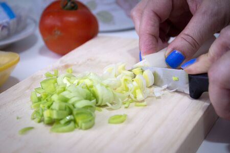 Sliced leek on a wooden cutting board. No people