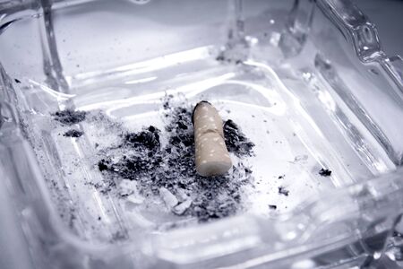 Cigarette consumed in an ashtray with ashes. No people
