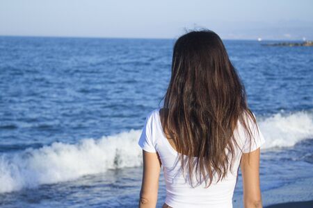 Girl dressed in white with the sea on her back. Tranquil scene