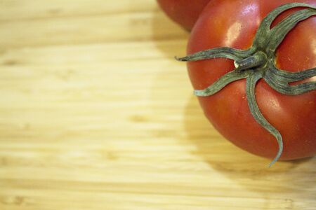 Two red ripe tomatoes on wooden cutting board. No peopleの写真素材