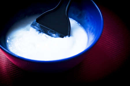 Blue bowl with mix to dye hair. Dye palette inside the mixing bowlの写真素材