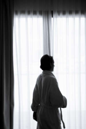 Silhouette of woman with bathrobe in front of a window. Sad atmosphereの写真素材