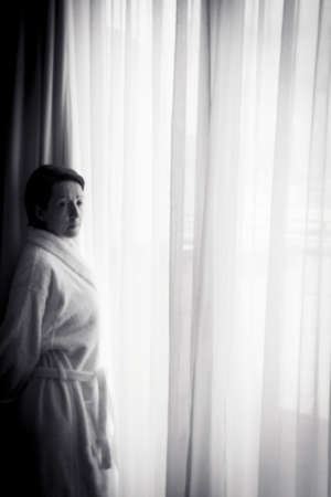 Silhouette of woman with bathrobe in front of a window. Sad atmosphereの写真素材