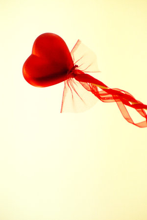 Red heart attached to a stick with a bow hanging. Copy spaceの写真素材