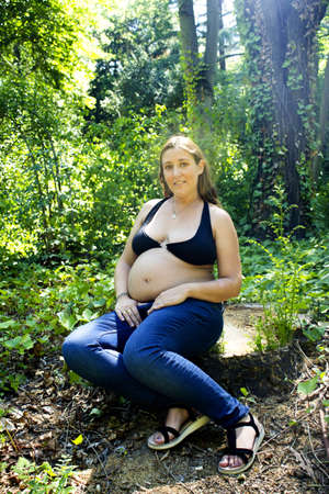 Seven month pregnant woman in a park dressed in jeansの写真素材