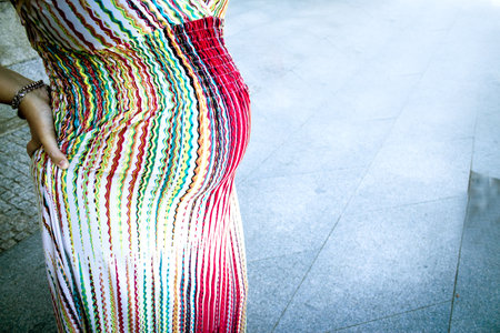 Seven month pregnant woman outdoors in multi colored striped dress. Day sceneの写真素材