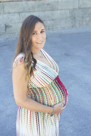 Seven month pregnant woman outdoors in multi colored striped dress. Day sceneの写真素材