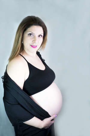 Eight month pregnant woman with bare belly. Happy emotionの写真素材