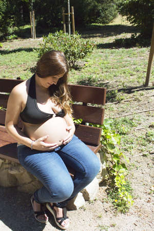 Seven month pregnant woman in a park dressed in jeansの写真素材