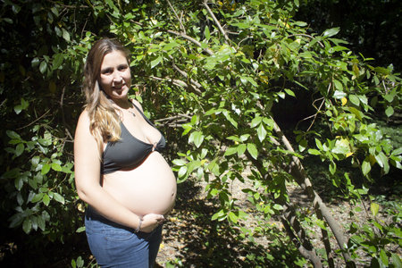 Seven month pregnant woman in a park dressed in jeansの写真素材