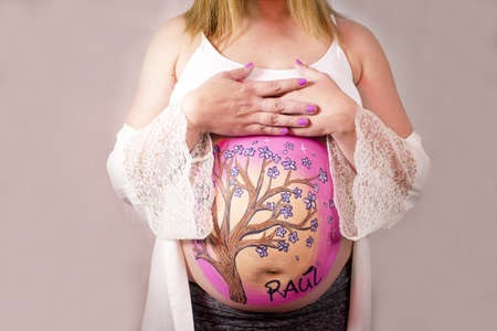 Eight months pregnant woman in dressing gown with drawing on her belly. No copy spaceの写真素材