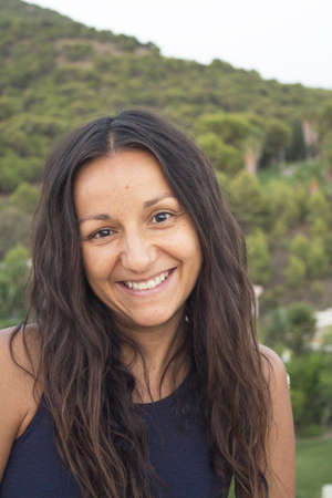 Portrait of young woman on mountain background. Smiling.