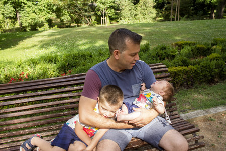 Father with his two sons sitting in a parkの写真素材