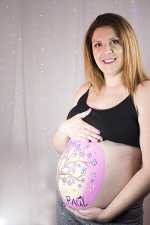 Pregnant woman with belly art against sparkly backdropの写真素材