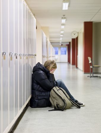 Young woman crying by the lockers at school の写真素材