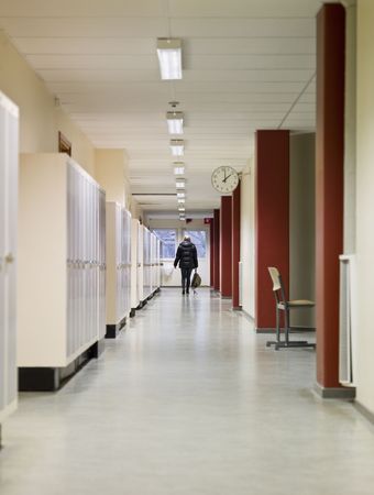 Young woman walking away through a corridor at schoolの写真素材