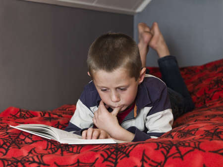 Young Boy in the bed reading a bookの写真素材