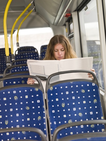 Lonley woman reading the newspaper on the busの写真素材