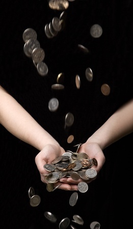 Raining coins in hands towards black backgroundの写真素材