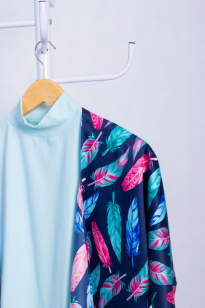 Blue T-shirt hanging on a clothes hanger on white backgroundの写真素材