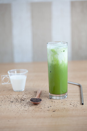 Iced Green matcha tea mixed with ice cube and milk in latte glass on white. Space for text. Close up.の写真素材