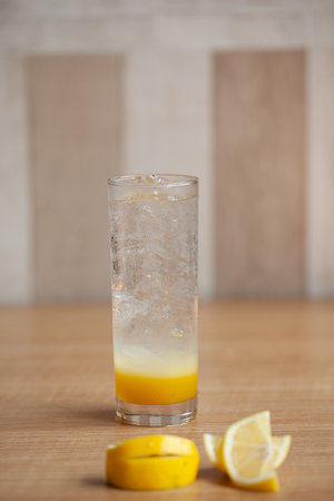 Lemon juice or lemonade with yellow limon sliced isolated on wooden table background. Copy space.の写真素材