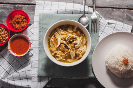 Soto Ayam is a authentic recipe from Indonesia especially Java. Served with cabbage, boiled egg, and chilli sauce. Top view on white bowl. Soto ayam is a kind of chicken soupの写真素材