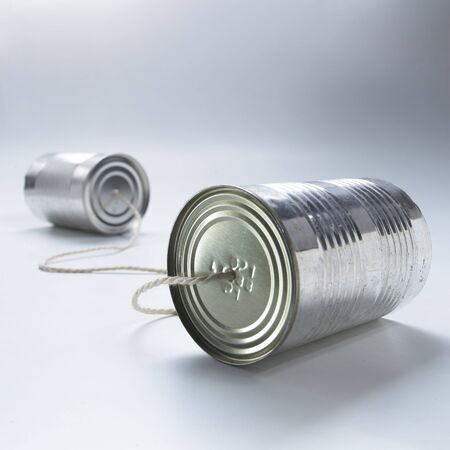 two tin cans connected by a piece of stringの写真素材