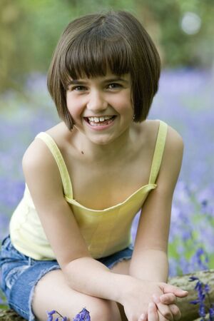 young female child sitting in a field of bluebellsの写真素材