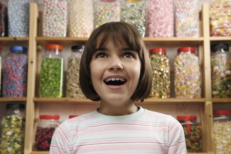 young girl smiling in awe at rows of sweetsの写真素材