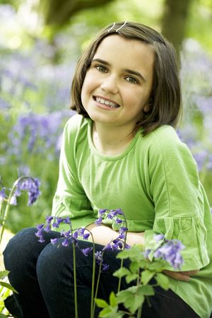 young girl sitting in a wood full of bluebellsの写真素材