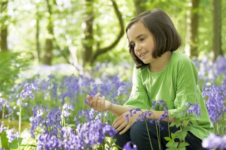 young girl sitting in a wood full of bluebellsの写真素材
